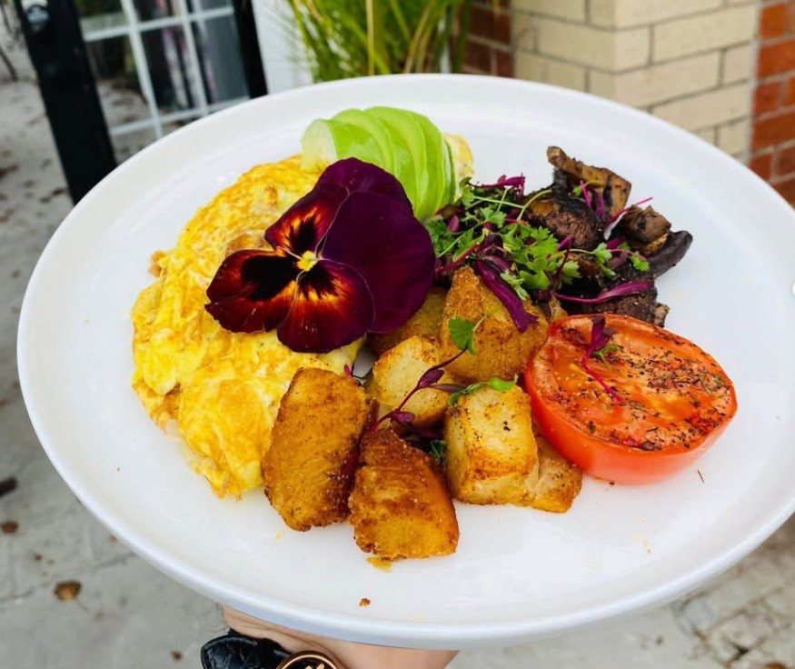 Brunch plate with eggs, crispy potatoes, roasted tomato and avocado